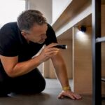 Une personne examine minutieusement une maison à l’aide d’une lampe de poche.