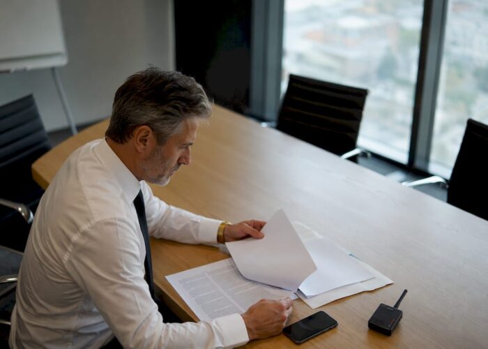 Un dirigeant en pleine réunion, attentif à son smartphone pour consulter ses messages importants.