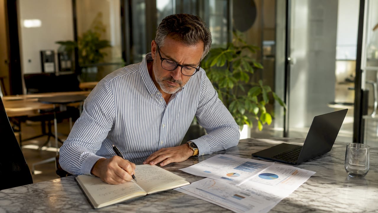Définition d'une enquête de solvabilité : guide complet 1 Un homme plongé dans l’analyse de documents financiers, installé à la terrasse d’un café.